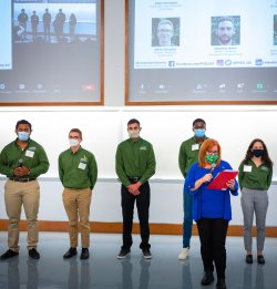 green team members staing on stage with presenter