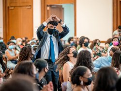 Summer academy graduate in suit and tie holding his hands together above his head, united