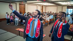 President Koppel and Daniel Jean posing for selfie in front of the crowd of students.