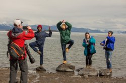 IIE passport students pose for photo on rocks on the shore of a lake