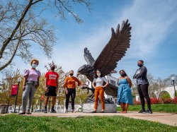 Six students in masks standing outside in front of Montclair State's hawk statue