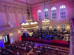 Two chandeliers over a ballroom with a stage along the back wall