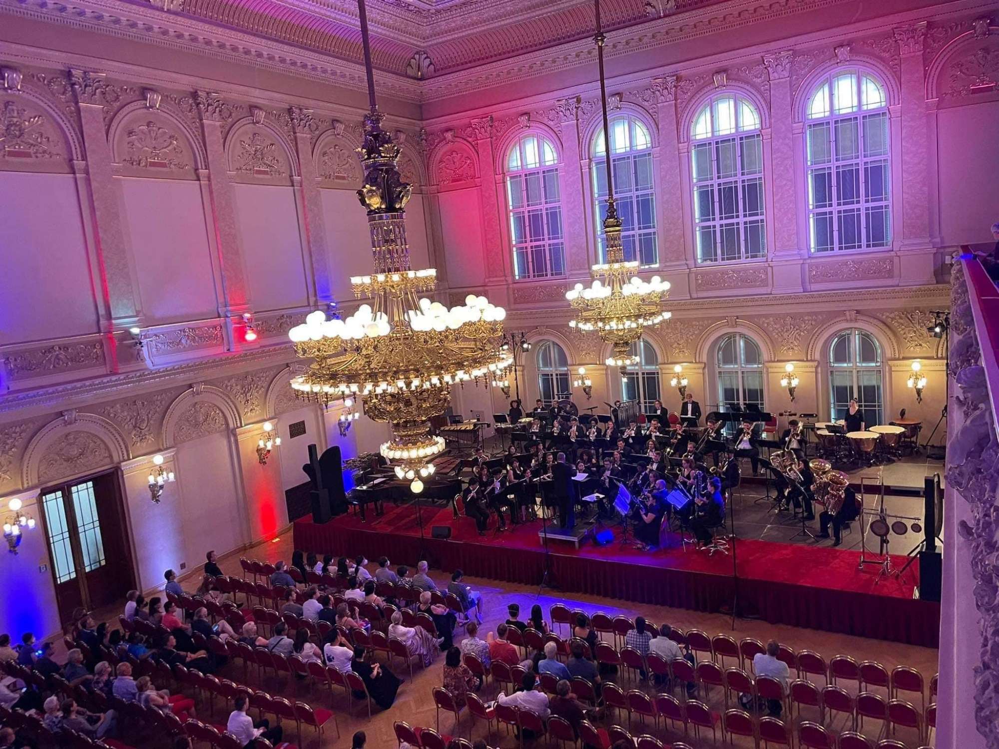 Two chandeliers over a ballroom with a stage along the back wall
