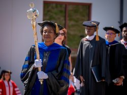 Sandra Adams leads the procession holding the University mace