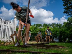 Student volunteer breaking apart scrap wood