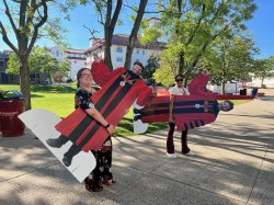 two ambassadors carrying cardboard cutouts of President Koppell
