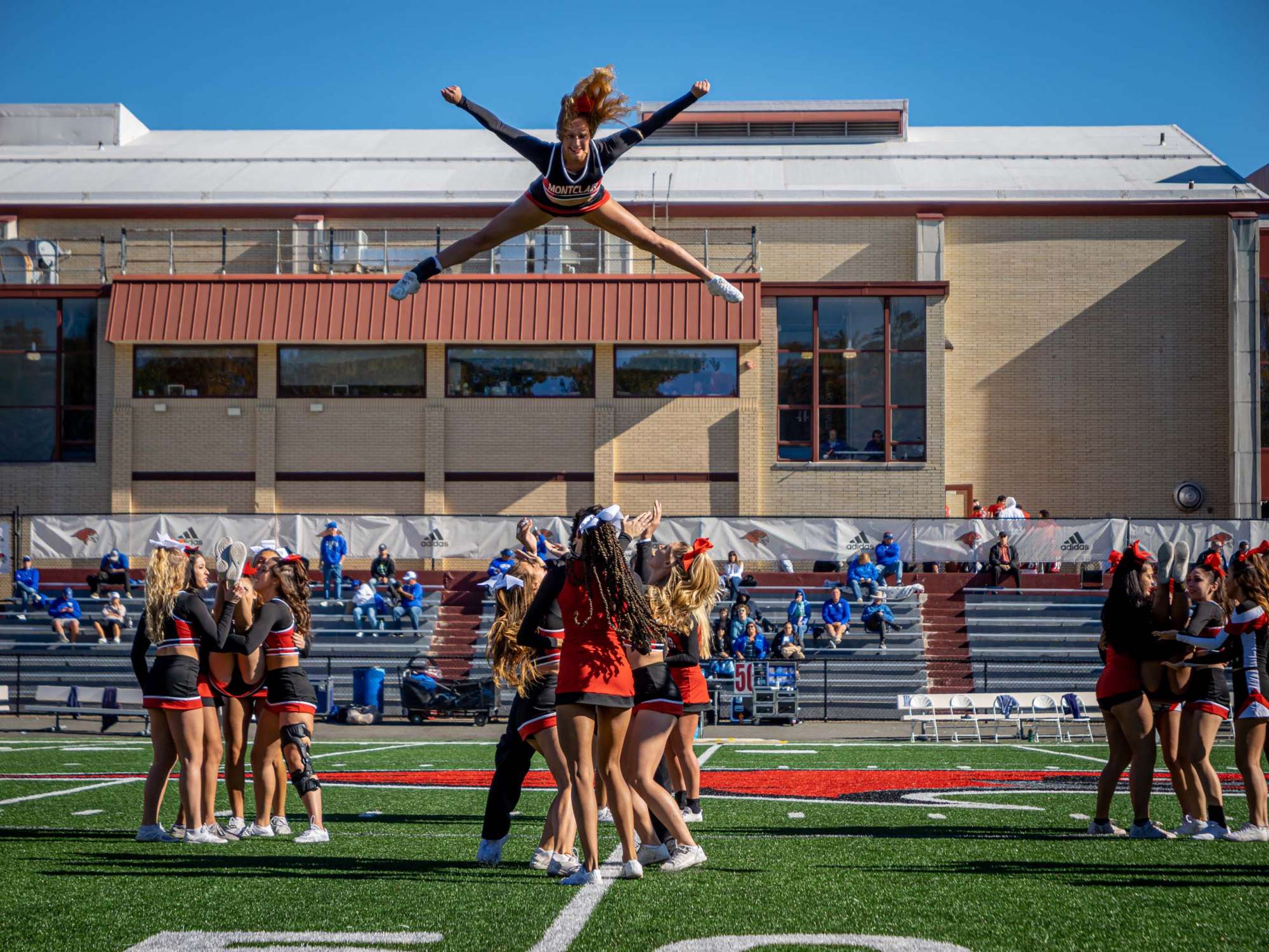 Cheerleaders on the field, one mid-flight above team