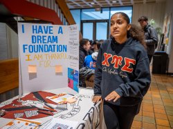 A female student stands at a table and speaks.