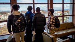 Four students look out a window at the view of New York City.