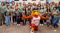 A Red Hawk mascot poses for a photo with students.
