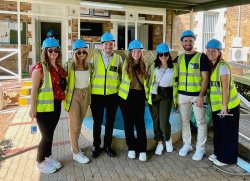oup of students pose wearing protective hard hats.