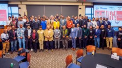A large group of Black and Latinx men of various ages pose for a photo.