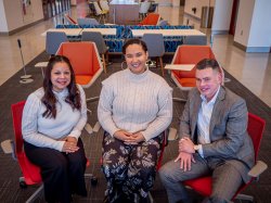 Three people sit and smile for the camera.