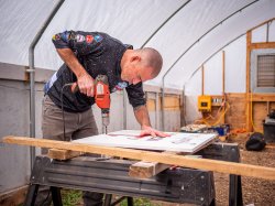 Man uses drill on sign.