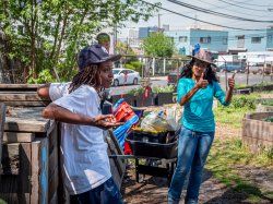 A person gives two thumbs up as a worker looks on.