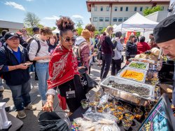 A woman wearing red looks at cups of veggies that include black beans.