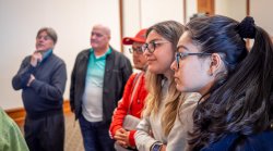 Several people listen intently as someone not pictured explains research.
