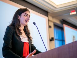 A female student speaks from a lectern.
