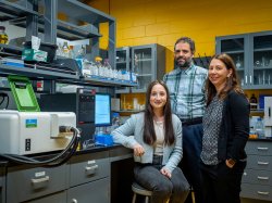 Three people pose in a science lab.