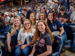 A crowd of spectators with six women smiling at the camera.