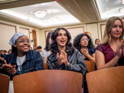 Women in an audience smile and applaud