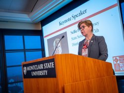 Senator Pou speaks at a podium that has a Montclair State University sign on it.