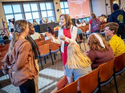 Five students talk with a woman dressed in red.