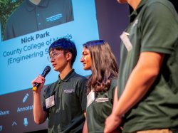 A student talks into a microphone as others look on.