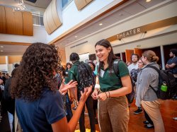 Students talk to each other in a theater lobby.