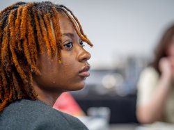 A student listens intently to a speaker not seen.