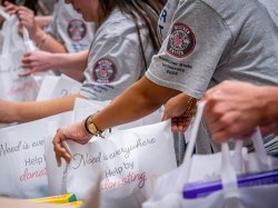 Students wearing Montclair NextGen T-shirts load bags with food.