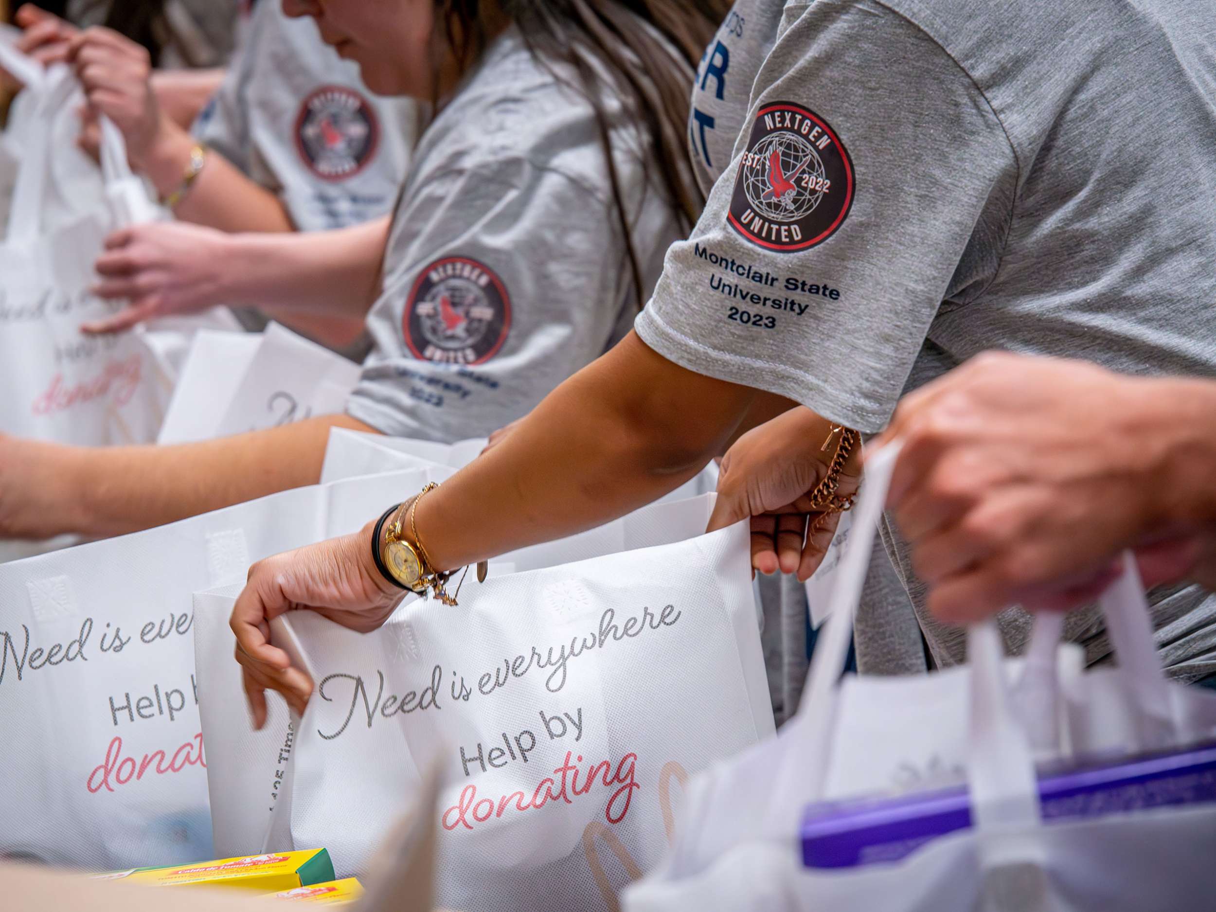 Students wearing Montclair NextGen T-shirts load bags with food.