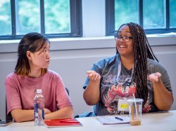 A student looks at another student who is gesturing while speaking.
