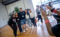 Four female students pose with a male mentor as someone takes a photo with a cell phone camera.