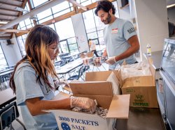 A student and the college president unpack boxes.