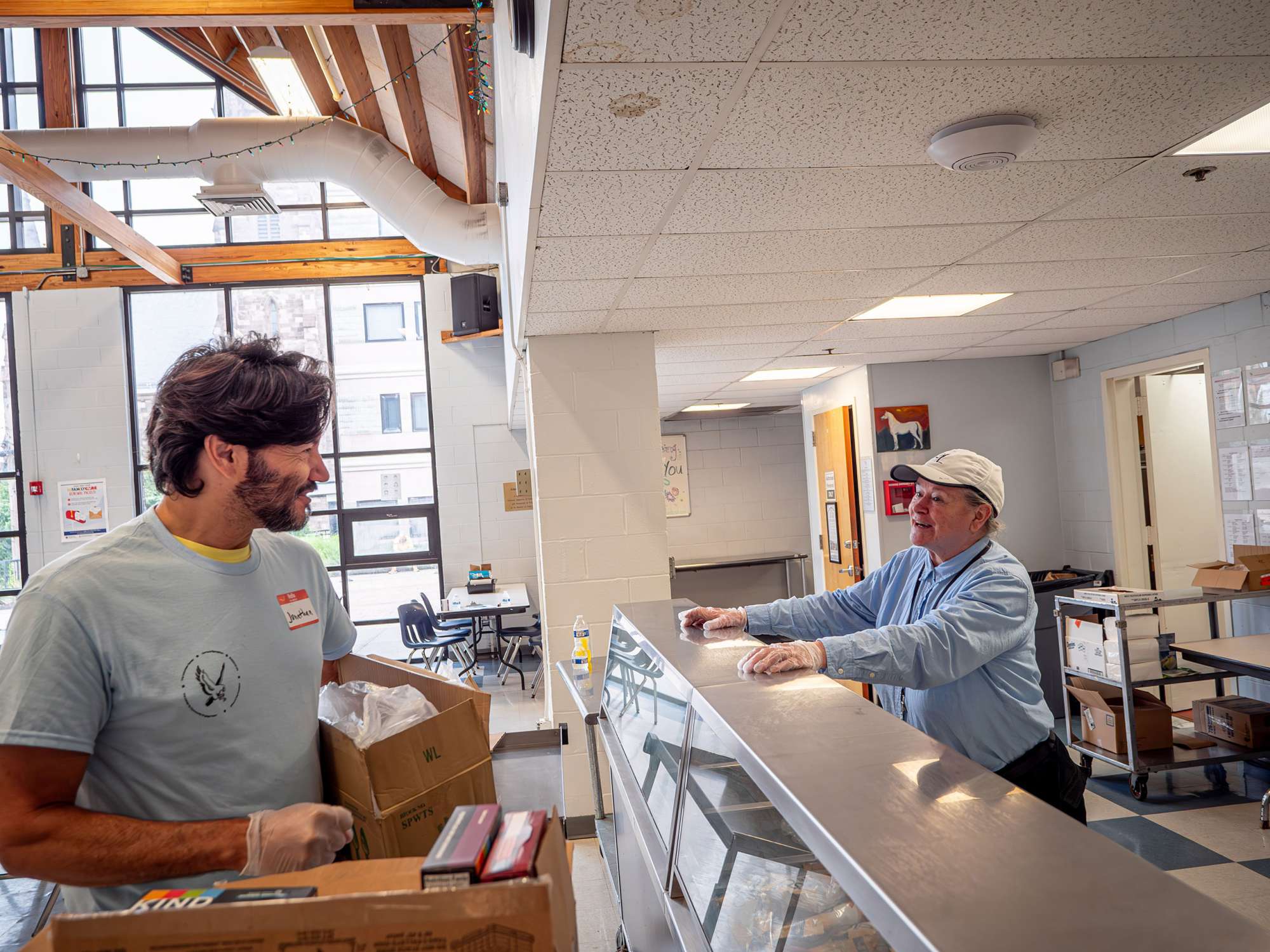 President Jonathan Koppell talks to a staff person standing behind a kitchen counter.