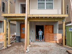 A young man stands inside a door at a construction site.