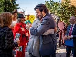 Two men embrace, celebrating the renaming of the building.