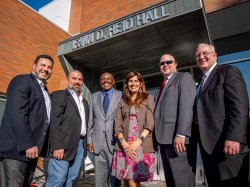 Six people stand in front of the sign that says Irvin D. Reid Hall