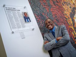 Irvin D. Reid stands in front of a plaque that says Dr. Irvin D. Reid, A Distinguished Leader.