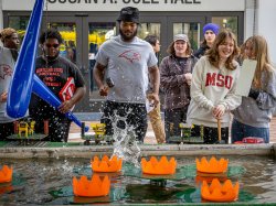 People play a carnival game involving water that is splashing.