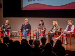 A panel of five women on stage.