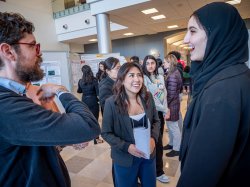 A man and two women talk and laugh during a science poster contest event.