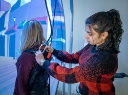 A student harnesses a fellow audiology student into the Bertec balance system.
