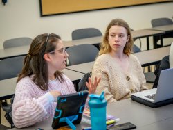 A student looks on as a classmate speaks in a classroom.