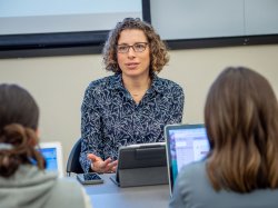 A professor gestures as she addresses her class.