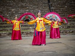 Three dancers wearing traditional Korean dress and with large fans.
