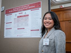 A student stands in front of her research poster.