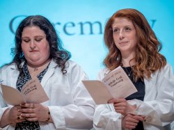 Gita Balser and Erin Douglas hold copies of the program, which includes the Audiology Oath.