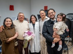 Wearing her white coat, Deborah Rivera poses for a photo with family members.